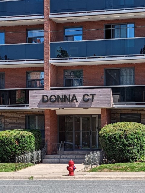 A red fire hydrant is in front of a building named Donna Court.