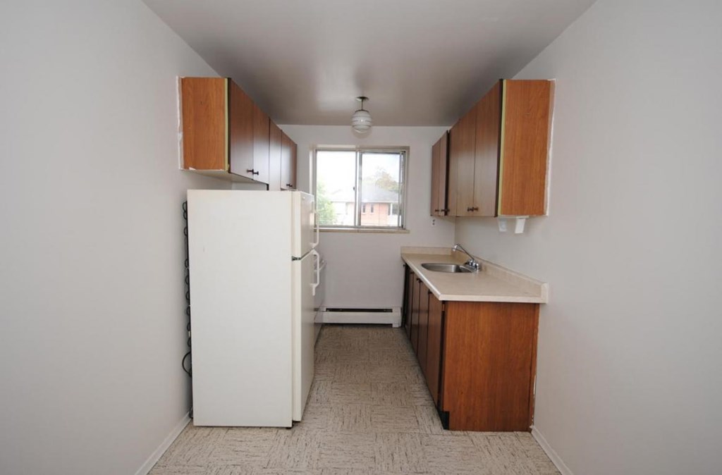 A kitchen with white appliances and wooden cabinets.