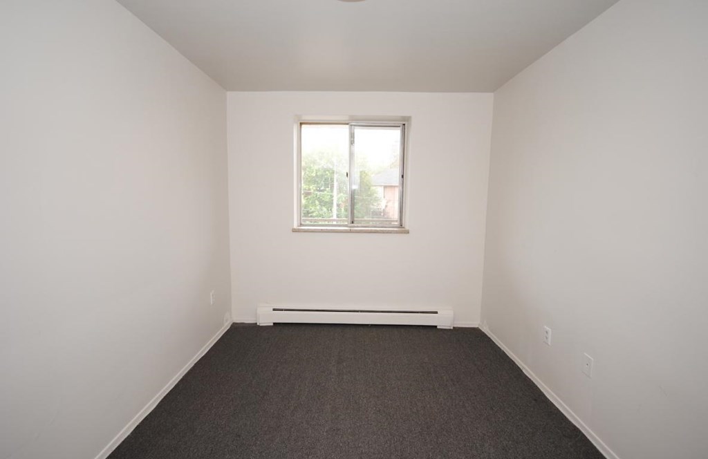 A room with a window and a radiator on the floor.