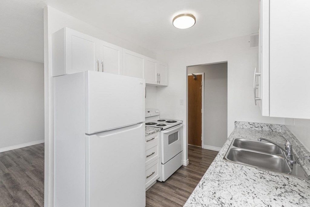 A kitchen with a white refrigerator, stove, and sink.