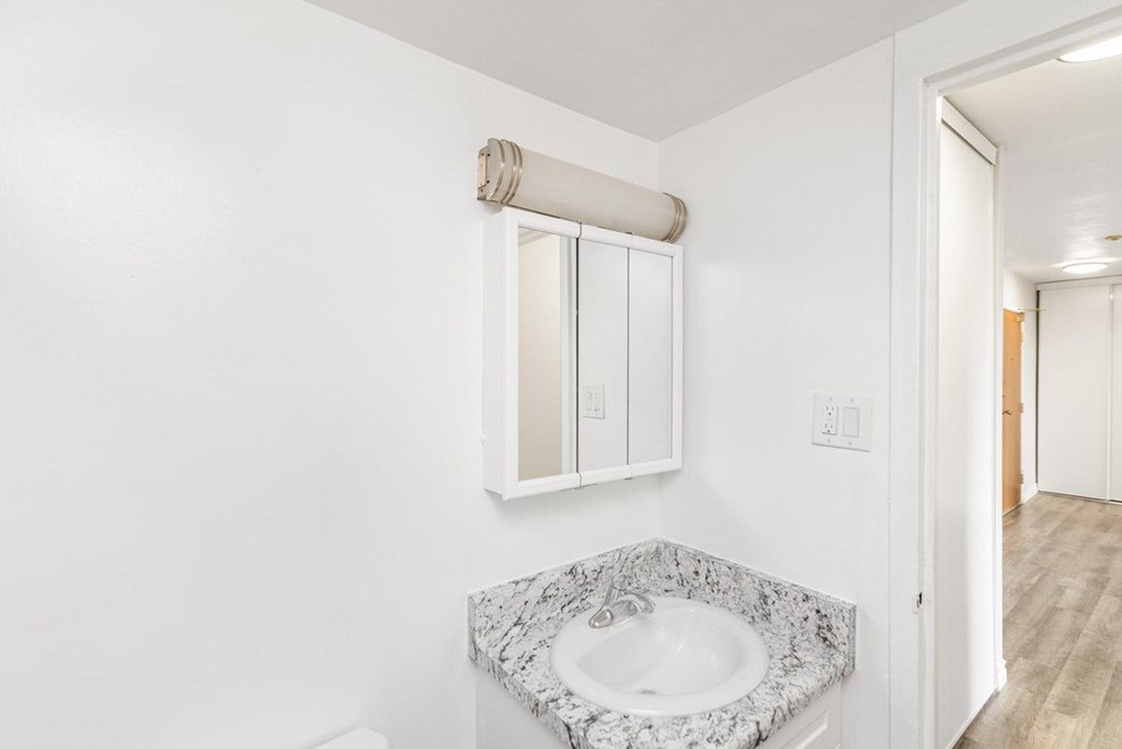 A bathroom with a marble sink and a window with blinds.