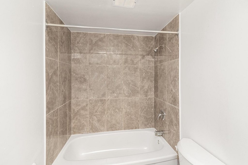 A bathroom with a tiled shower area and a bathtub.