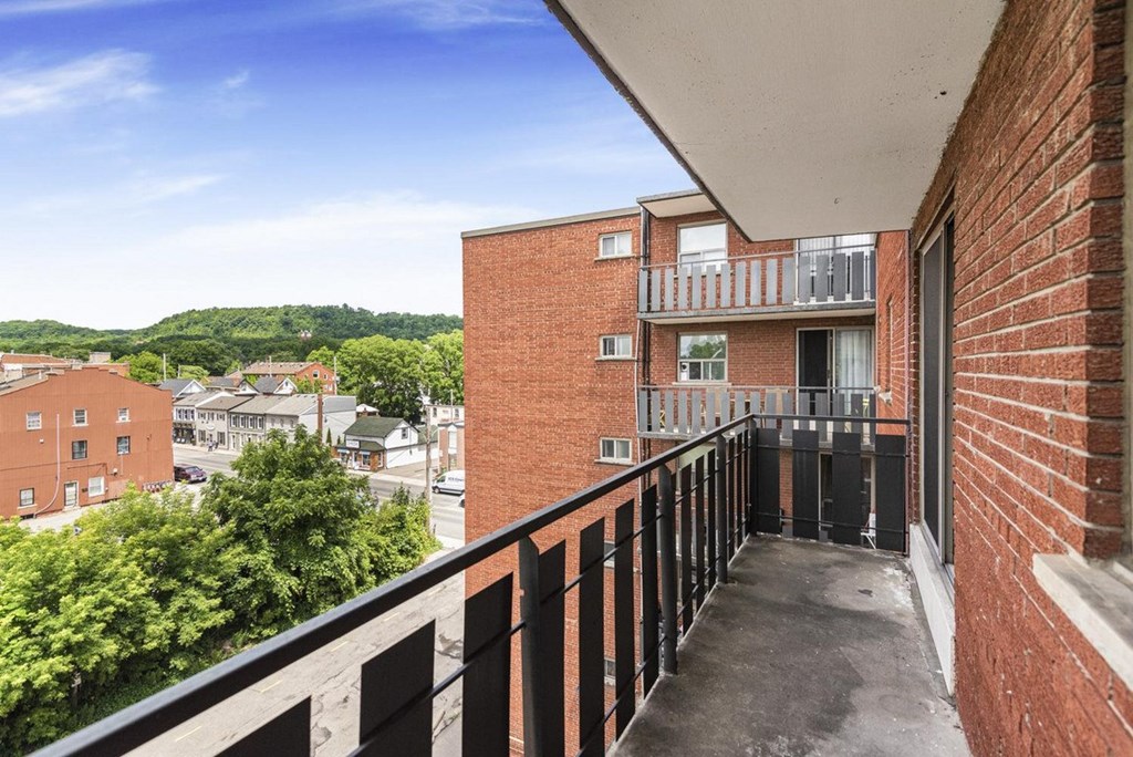 A balcony with black railings overlooks a residential area.