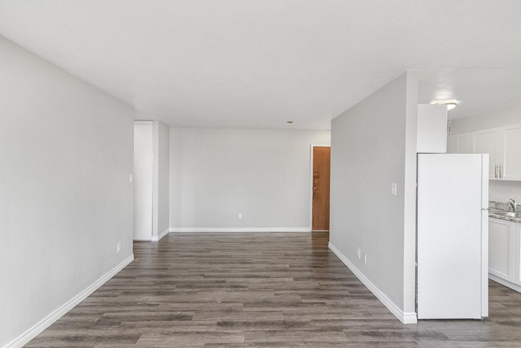 A spacious room with a wooden floor and white walls.