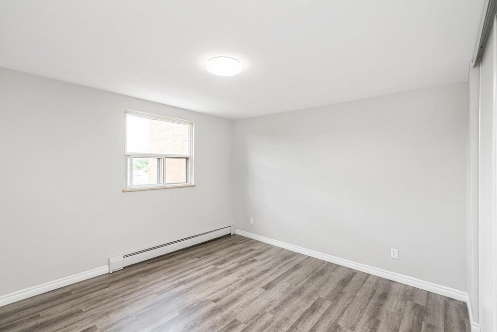 A room with a window and wooden flooring.