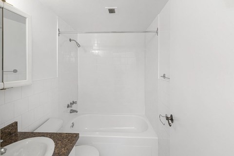 A white bathroom with a tub, sink, and mirror.