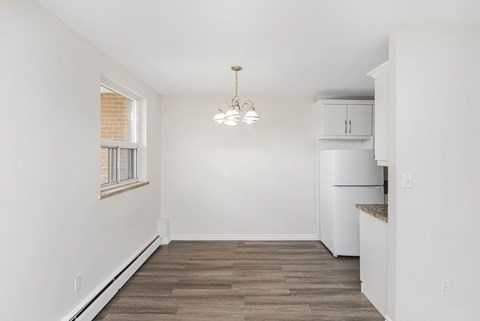 A kitchen with a white refrigerator and wooden flooring.