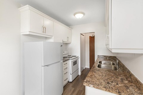A kitchen with white appliances and cabinets.
