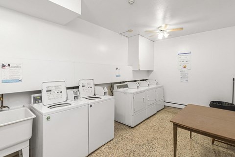 A laundry room with a washer and dryer, sink, and a table.