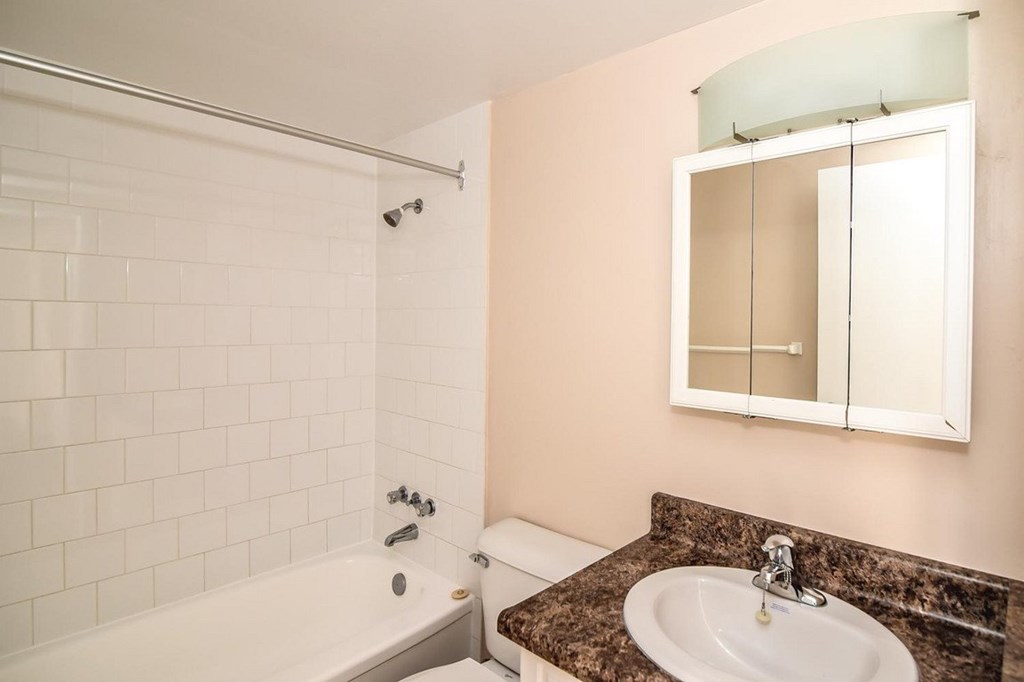 A bathroom with a white tub, sink, and mirror.
