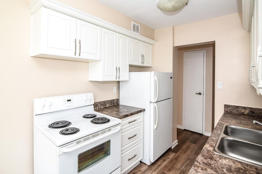 A kitchen with white appliances and wooden floors.