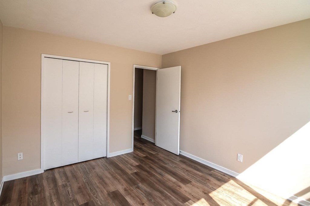 A room with a white door and a brown floor.