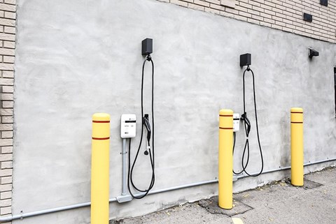 Three yellow poles with cables plugged into a wall socket.