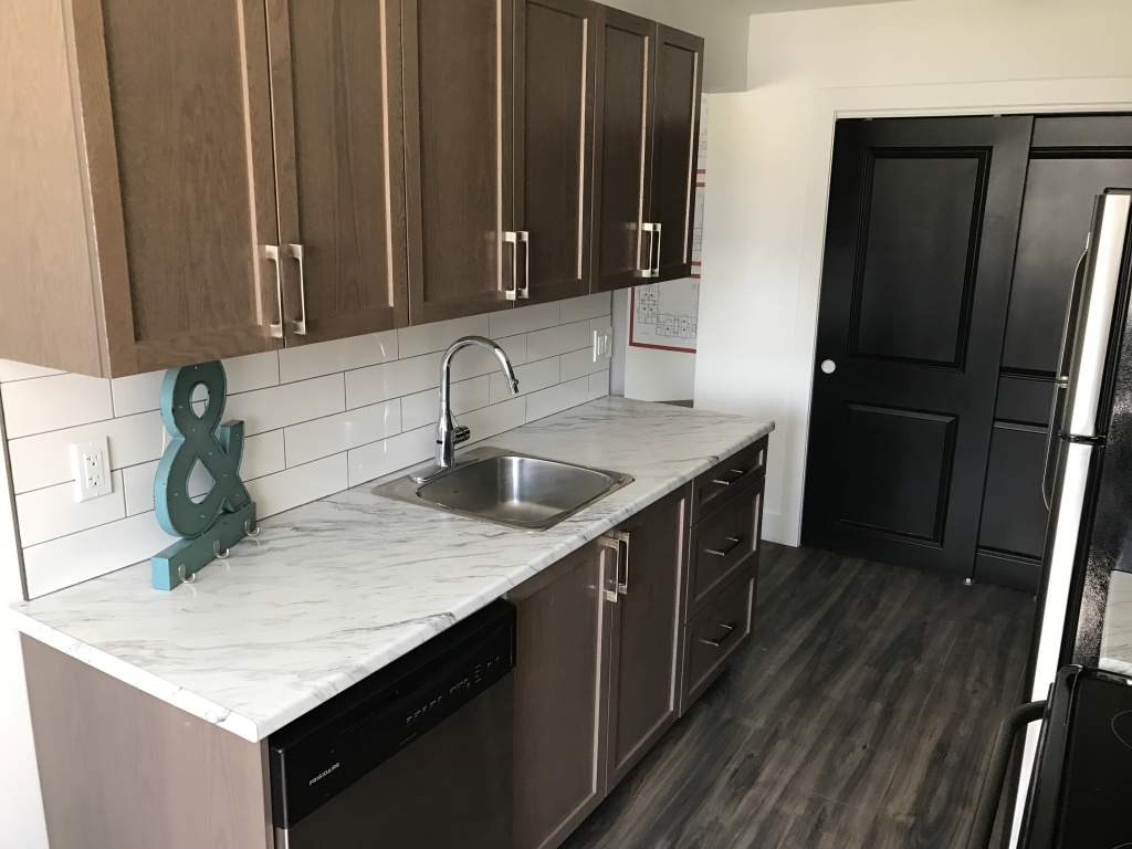 A kitchen with brown cabinets and a marble countertop.