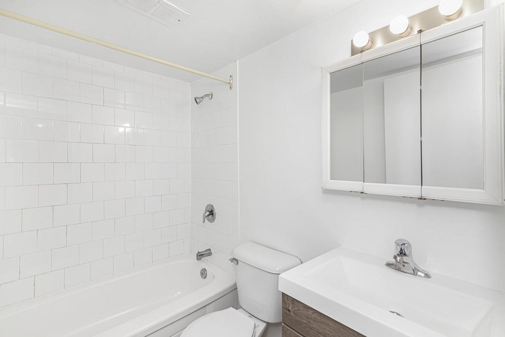 A white bathroom with a toilet, sink, and mirror.