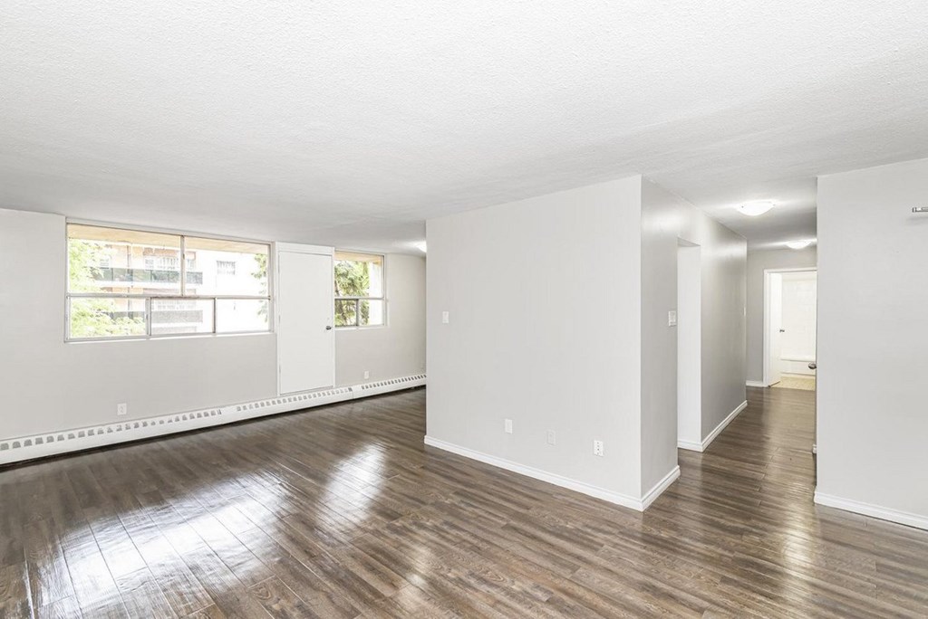 A large empty room with wooden floors and white walls.