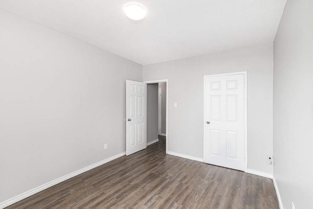 A room with a white door and a brown floor.