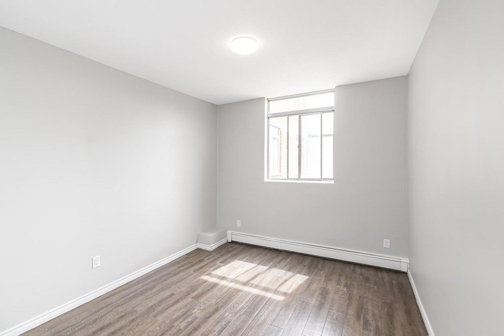 A room with a window and wooden flooring.