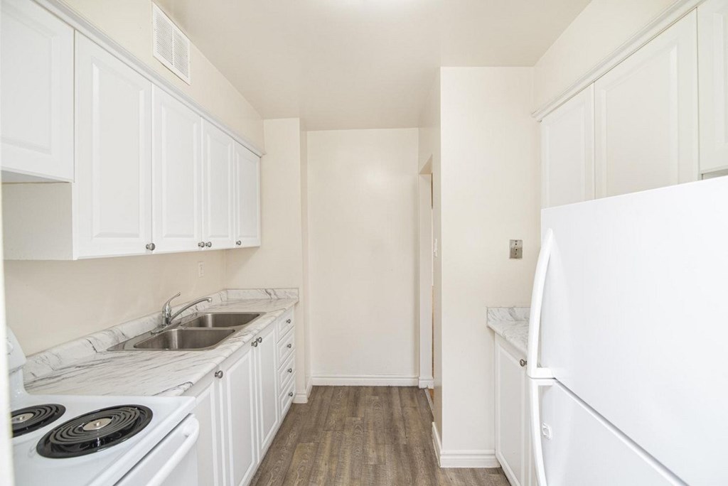 A kitchen with white cabinets and a stove top oven.