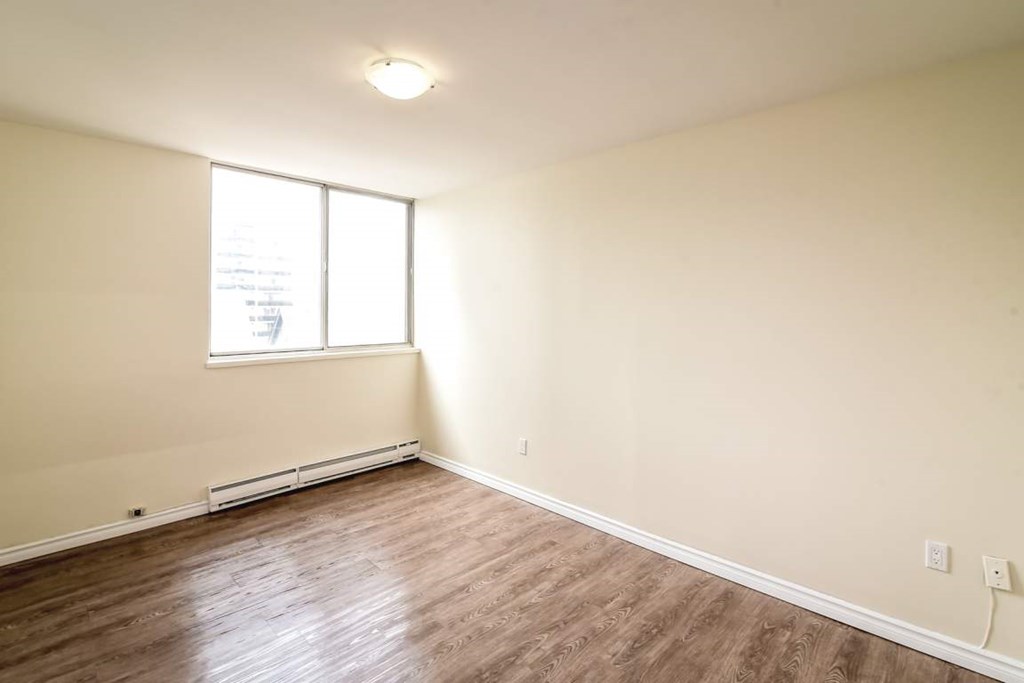 A room with a window and wooden flooring.