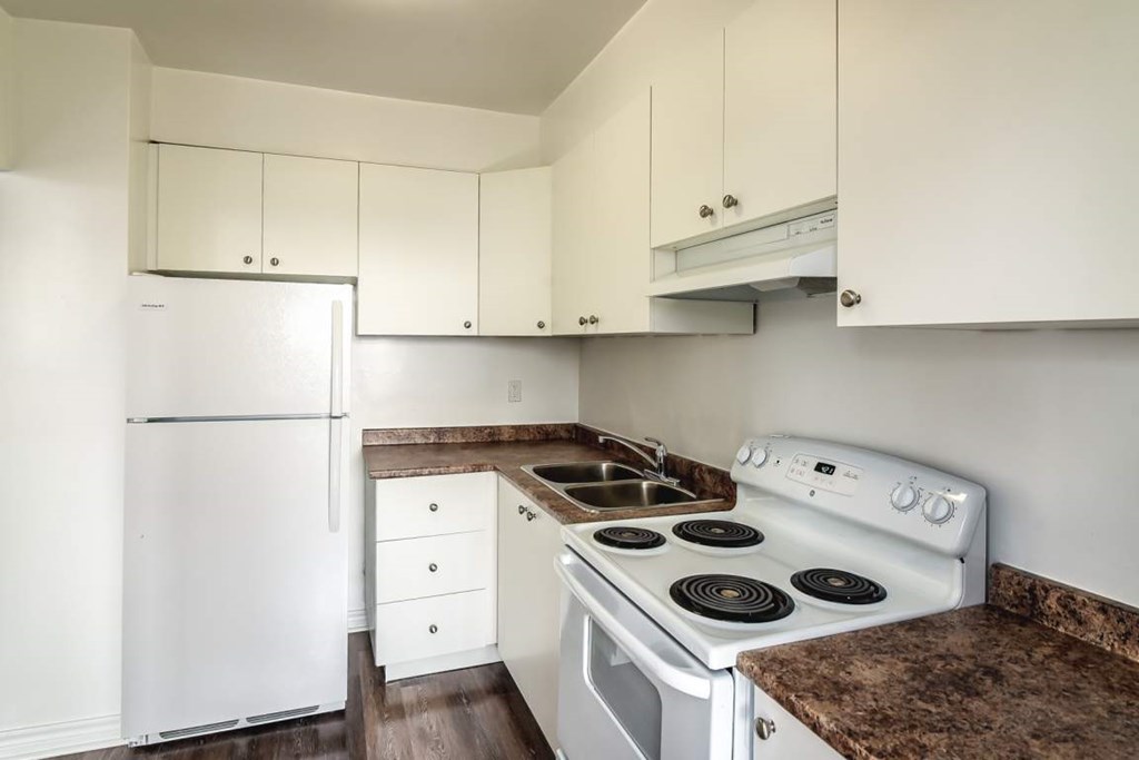 A white refrigerator and stove in a kitchen with white cabinets.