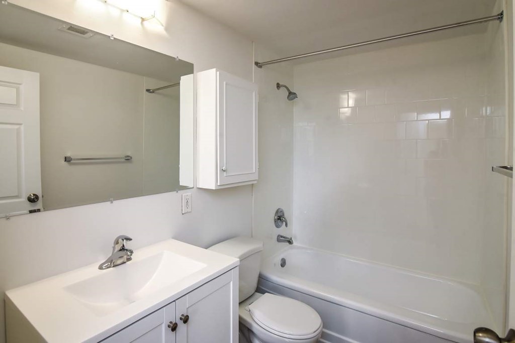 A white bathroom with a toilet, sink, and bathtub.