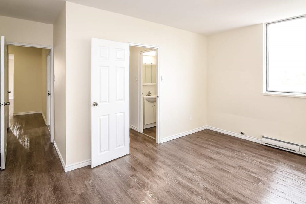 A room with a white door and a brown floor.