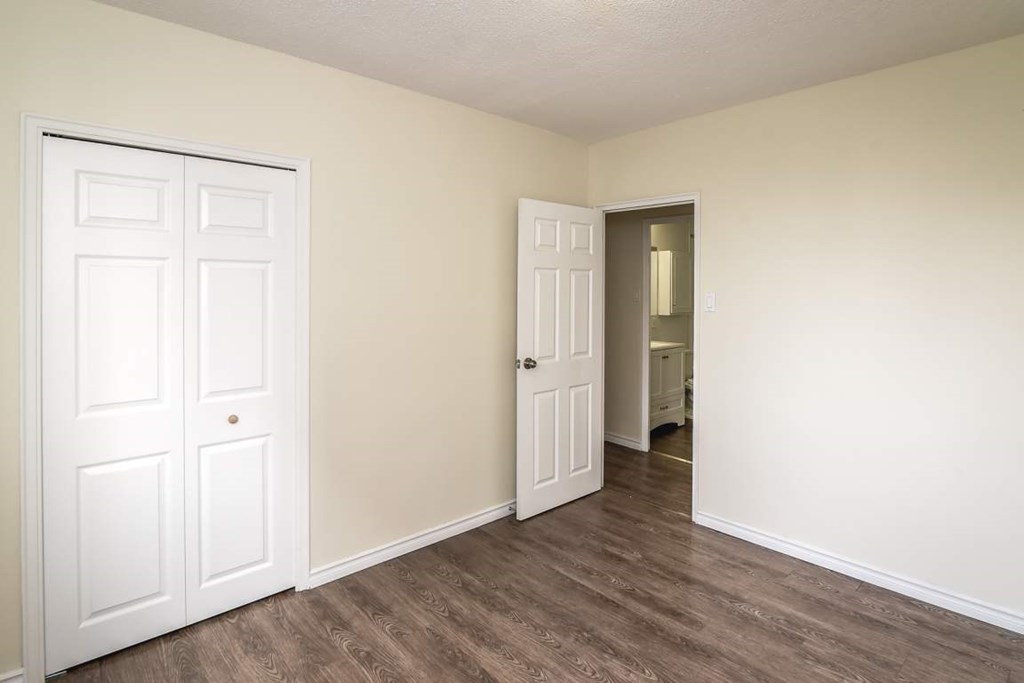 A room with a white door and a brown floor.
