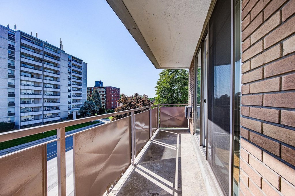 A balcony with a metal railing and a brick wall.