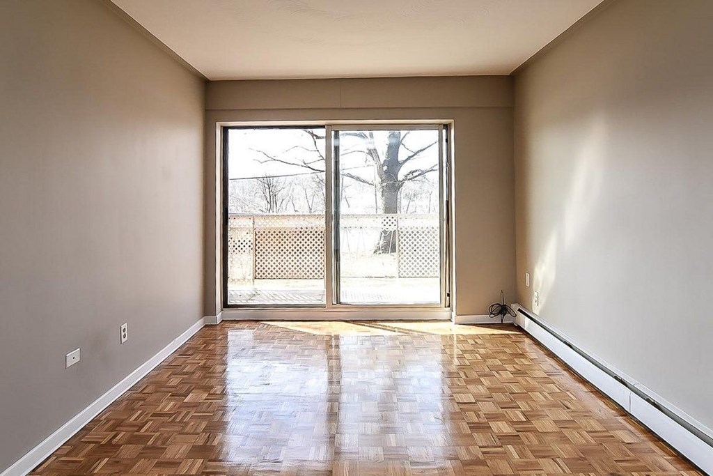 A room with wooden flooring and a sliding glass door leading outside.