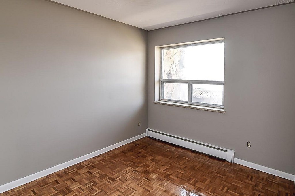 A room with a window and a wooden floor.