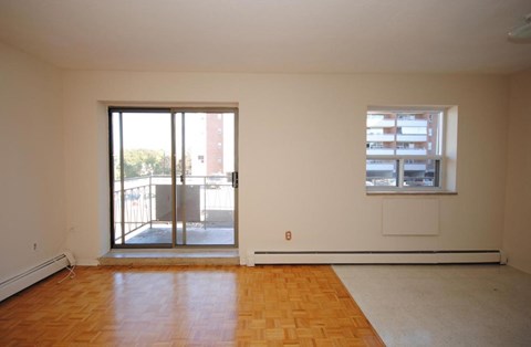 A room with a wooden floor and a window with blinds.