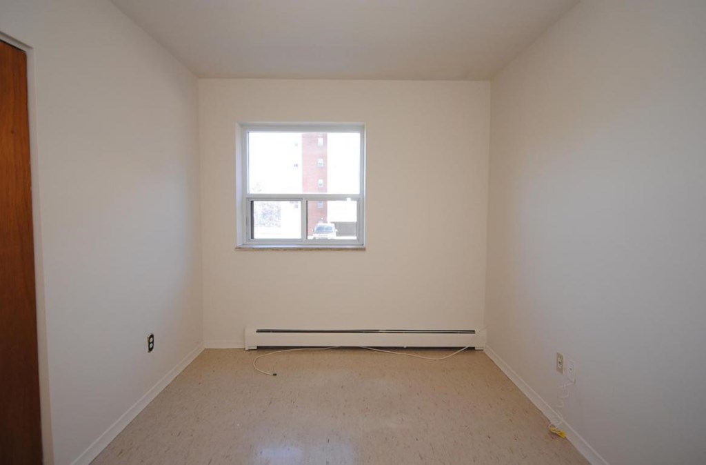A room with a window and a radiator on the floor.