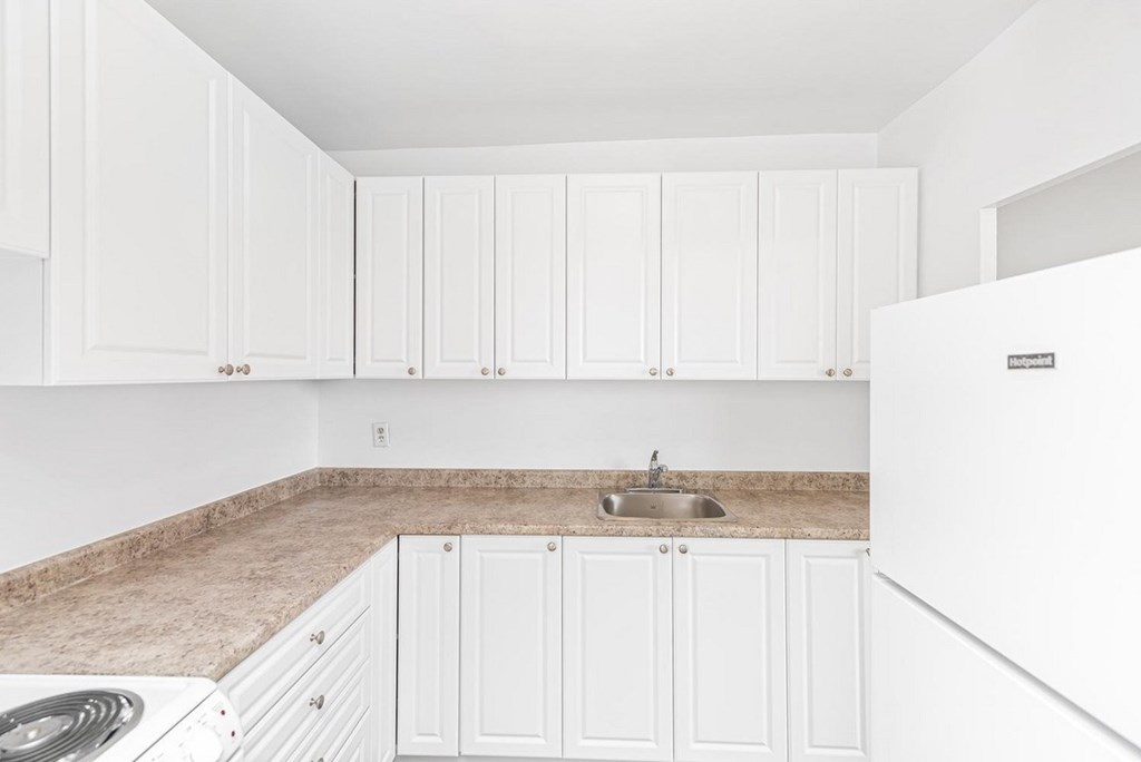 A kitchen with white cabinets and a brown countertop.