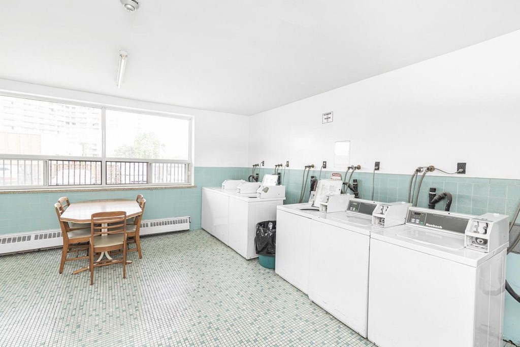A laundry room with a washer and dryer, a table and chairs, and a window.