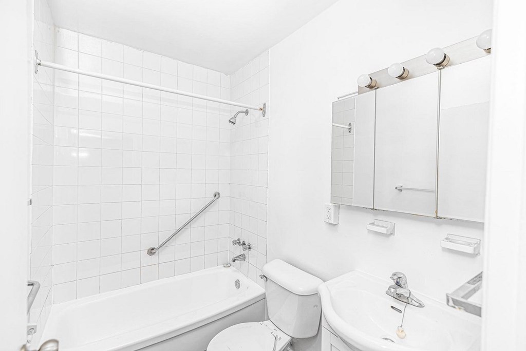 A white bathroom with a tub, toilet, and sink.