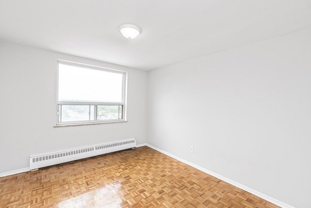 A room with a window and a radiator on the floor.