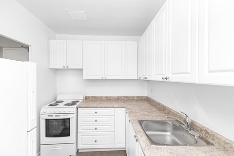 A white kitchen with a sink and a stove.
