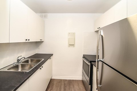 A small kitchen with a refrigerator, sink, and oven.