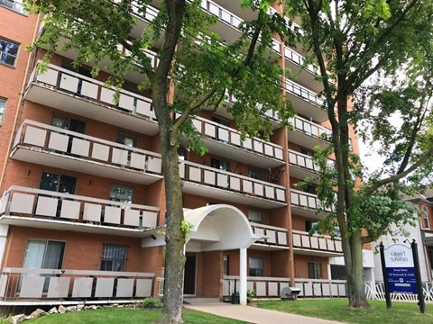 A tall apartment building with balconies and a blue sign in front.