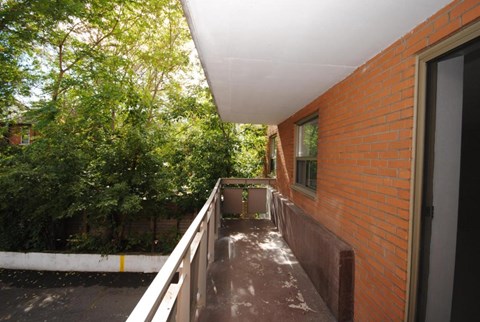A balcony with a white railing and a brick wall.
