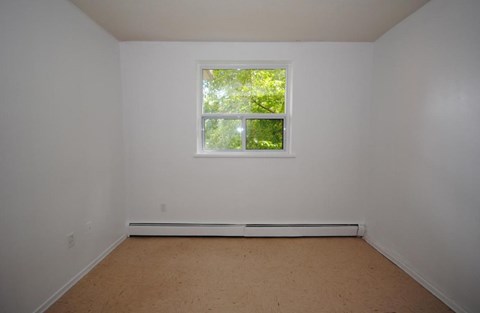 A room with a window and a white wall.