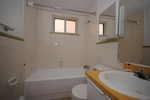 A white bathtub sits next to a toilet in a bathroom.