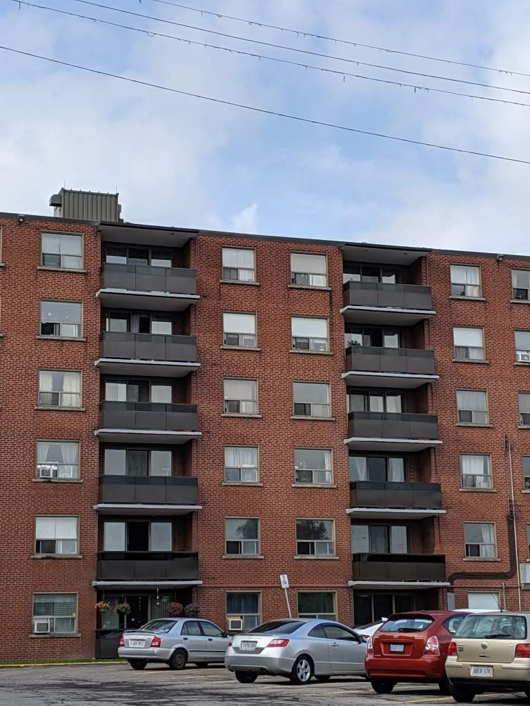 A red brick building with a parking lot in front of it.