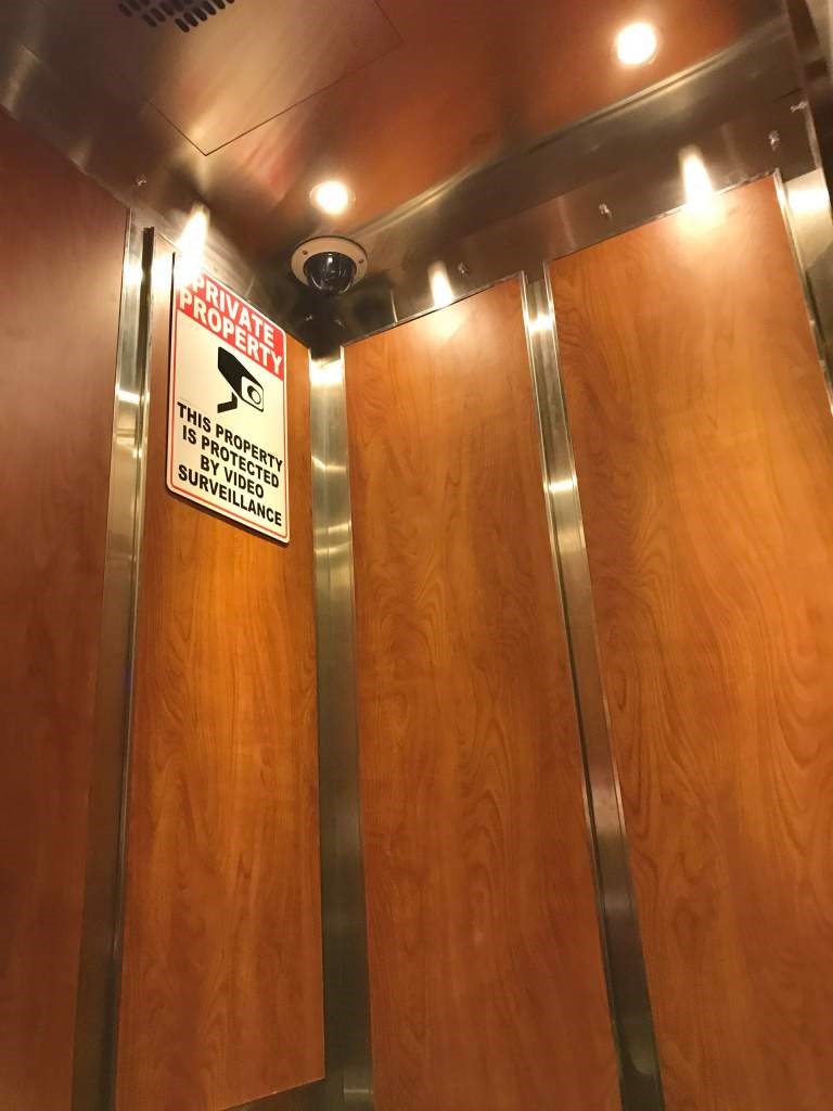 A sign on a door warning that the property is under surveillance.