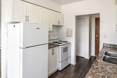A white refrigerator is in a kitchen with white cabinets.