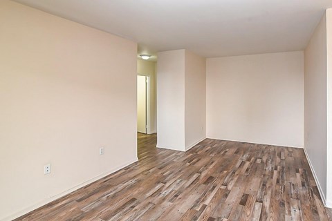 A room with wooden flooring and a doorway leading to another room.