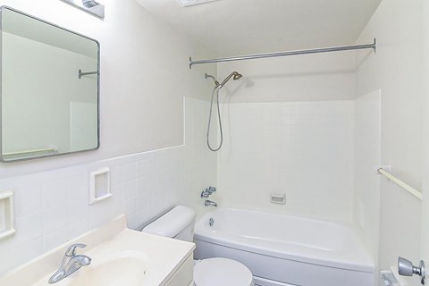 A white bathroom with a toilet, sink, and bathtub.