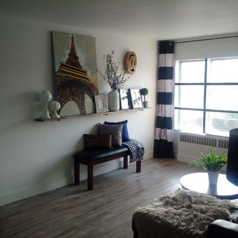 A living room with a wooden bench and a painting of the Eiffel Tower on the wall.