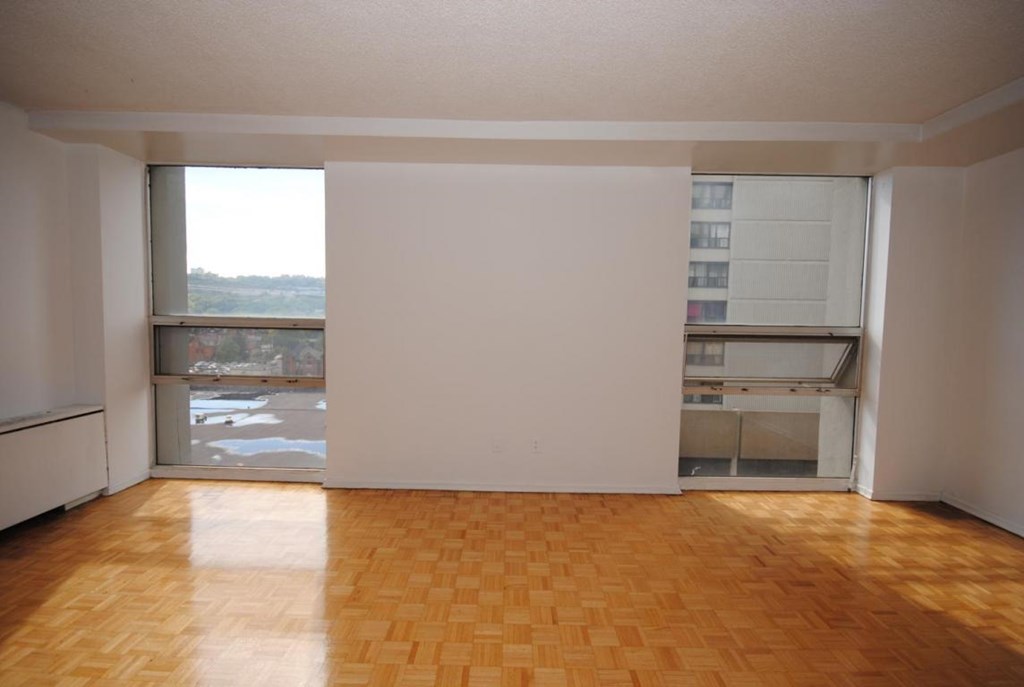 A room with a wooden floor and a window overlooking a body of water.
